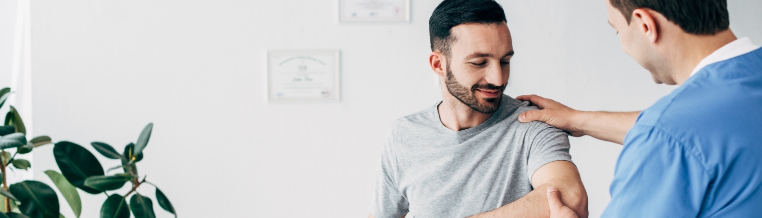 medical provider examining arm of patient and providing patient resources in clinic specializing in LGBTQIA+ health